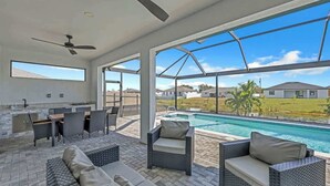 A spacious outdoor area with a pool, seating, and a kitchen area. - Coral Waters Modern Escape | Pool Home (Cape Coral)
