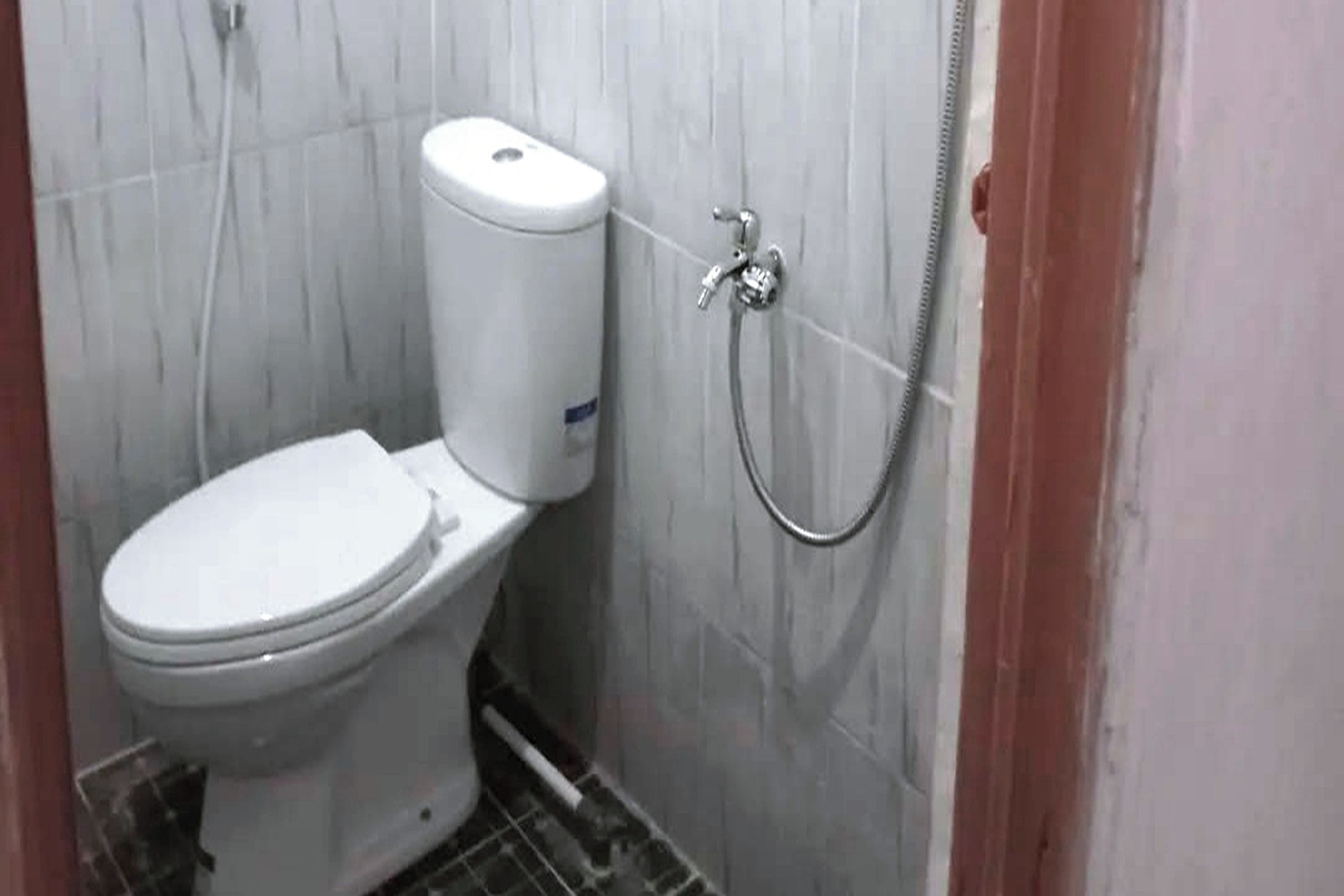 A small, compact bathroom with a toilet, a shower, and a wall-mounted toilet paper holder.