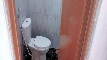 A small bathroom with a white toilet, tiled walls, and a black and white floor.