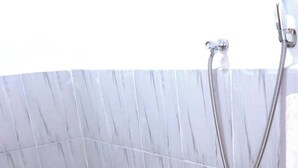Een badkamer met een marmeren wand en een douche met een handdouche.