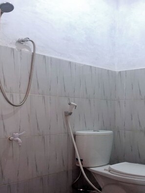 Un baño con ducha, inodoro y grifo mural.