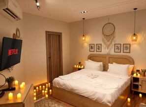 Une chambre à coucher bien aménagée, avec un lit, des tables de chevet, un téléviseur fixé au mur et des éléments décoratifs accrochés au mur.