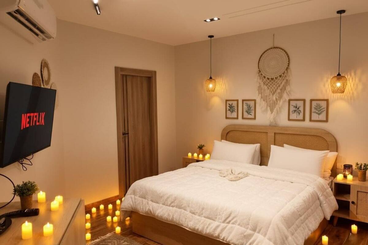 Un dormitorio ordenado con una cama grande, lámparas de noche, arte en la pared y un televisor de pantalla plana mostrando 'NETFLIX'.
