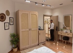 Een moderne slaapkamer met een grote kledingkast, een bureau met spiegel, en een kamerplant.
