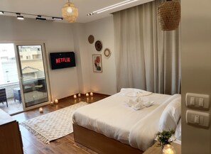 A modern bedroom with a large bed, a flat-screen TV, and a view of the outdoors. - Zen Pyramids Luxury Villa (Giza)