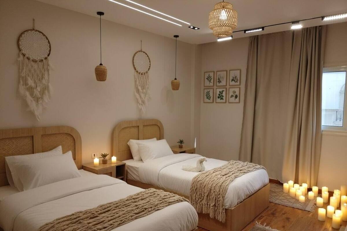 Un dormitorio con dos camas, un ventanal grande y adornos decorativos en las paredes.