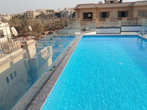 Une piscine sur le toit, avec une eau d’un bleu cristallin, entourée d’une rambarde en verre.