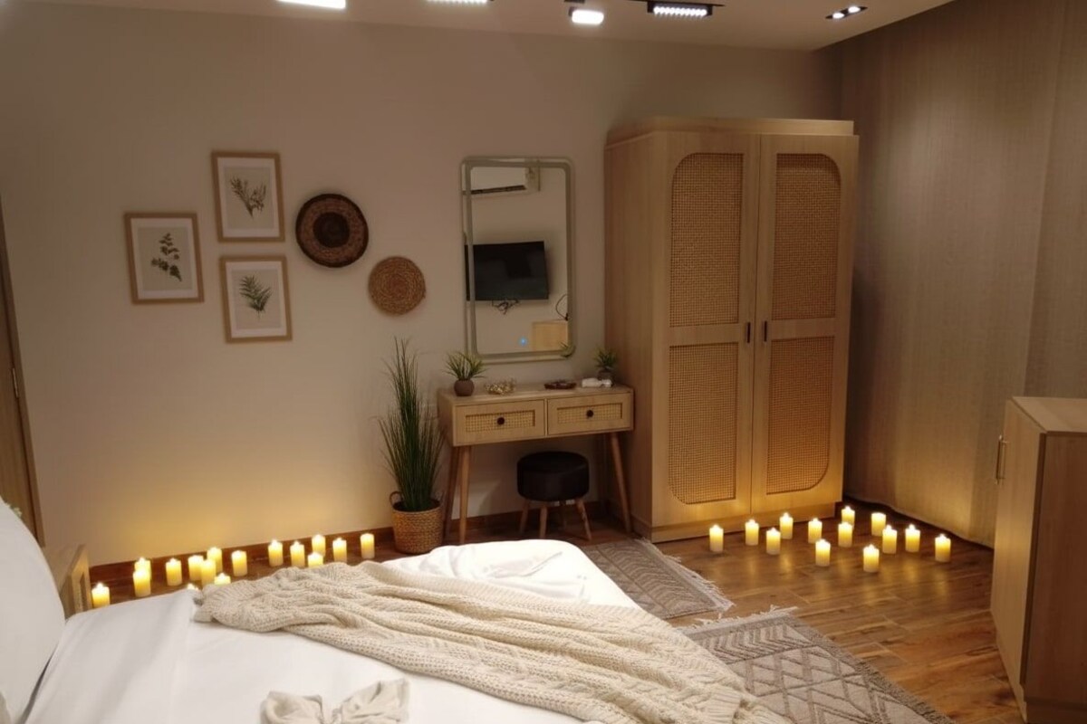 A bedroom with a bed, bedside table, mirror, wardrobe, and wall-mounted decor.