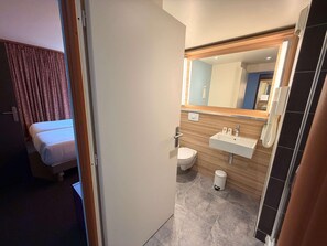 Ein Hotelzimmer mit Bett, einem Badezimmer mit Waschbecken, Toilette und Spiegel.