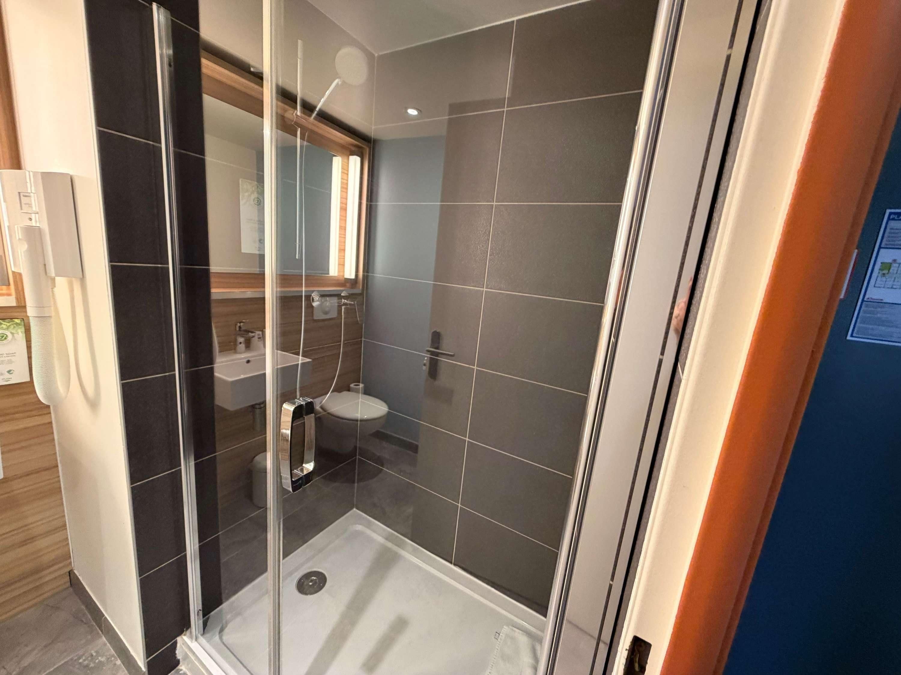 Un baño moderno con ducha de vidrio, lavabo e inodoro.