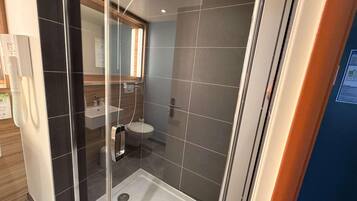 Un baño moderno con ducha de vidrio, lavabo e inodoro.