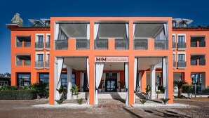 Un edificio de varios pisos con balcones, una entrada central y un letrero que dice "MIM SOTOGRANDES".