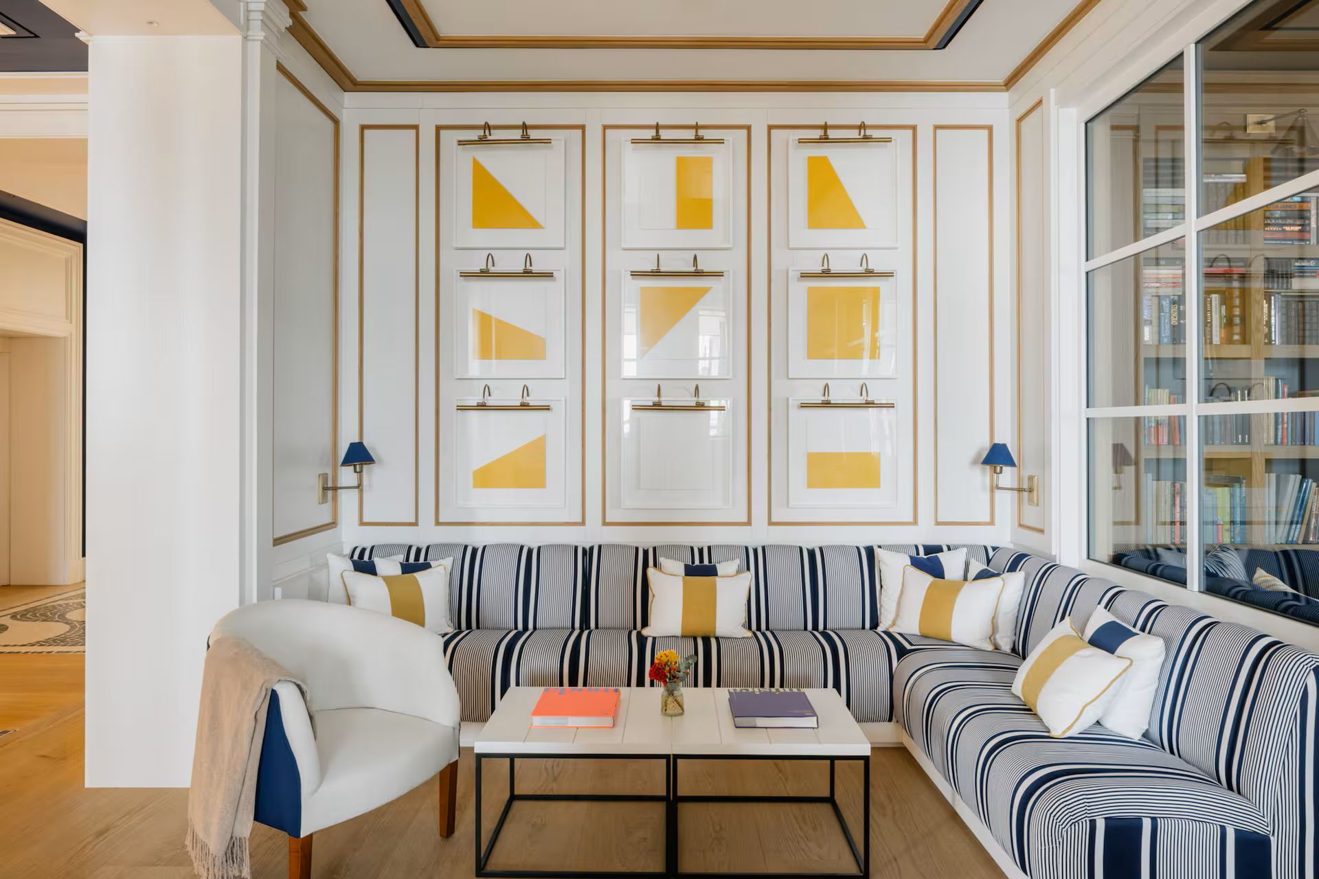Una sala de estar moderna con un sofá a rayas, una mesa de centro con libros y una estantería llena de libros.