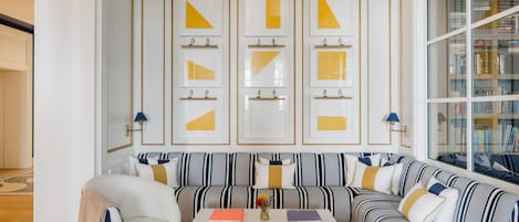 Una sala de estar moderna con un sofá a rayas, una mesa de centro con libros y una estantería llena de libros.