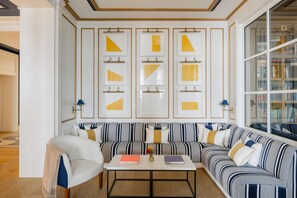 Un salon moderne avec un canapé à rayures, une table basse sur laquelle sont posés des livres et une bibliothèque remplie de livres.