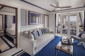 A modern hotel room with a large sofa, a coffee table, and a balcony with outdoor seating. - MIM Sotogrande Member of Meliá Collection (Cadiz)