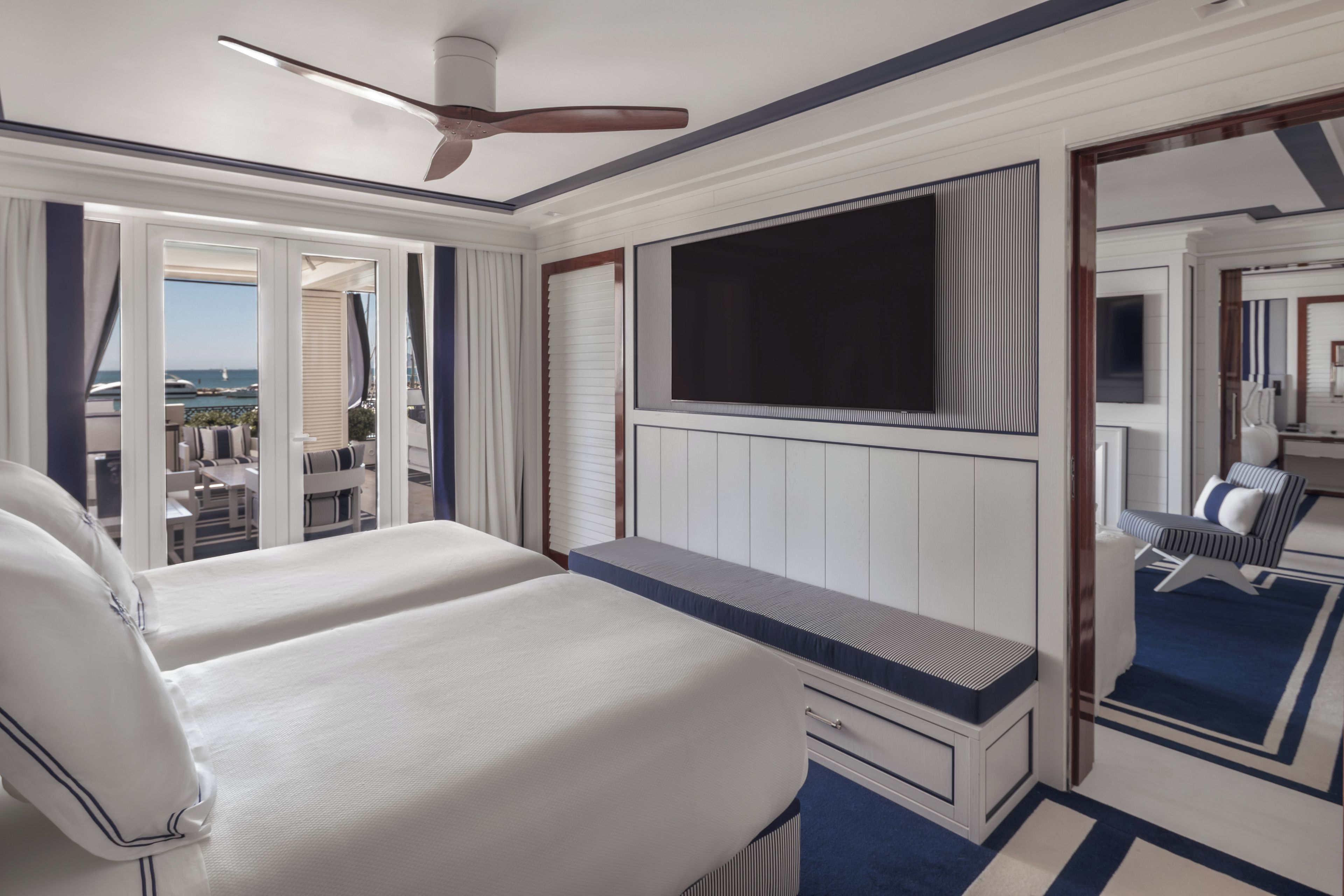 A hotel room with a bed, a desk, a TV, and a view of the ocean.