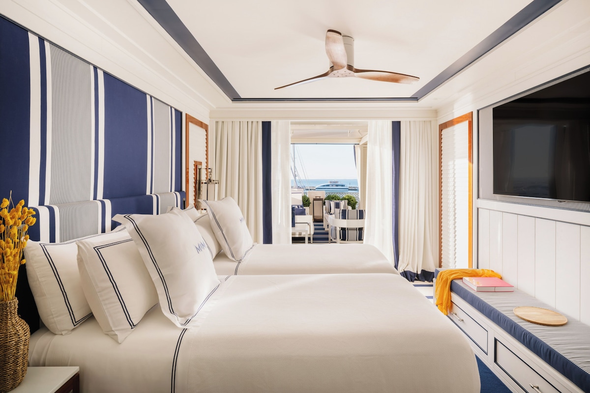 Une chambre d’hôtel avec un grand lit, un bureau et une vue sur la mer.