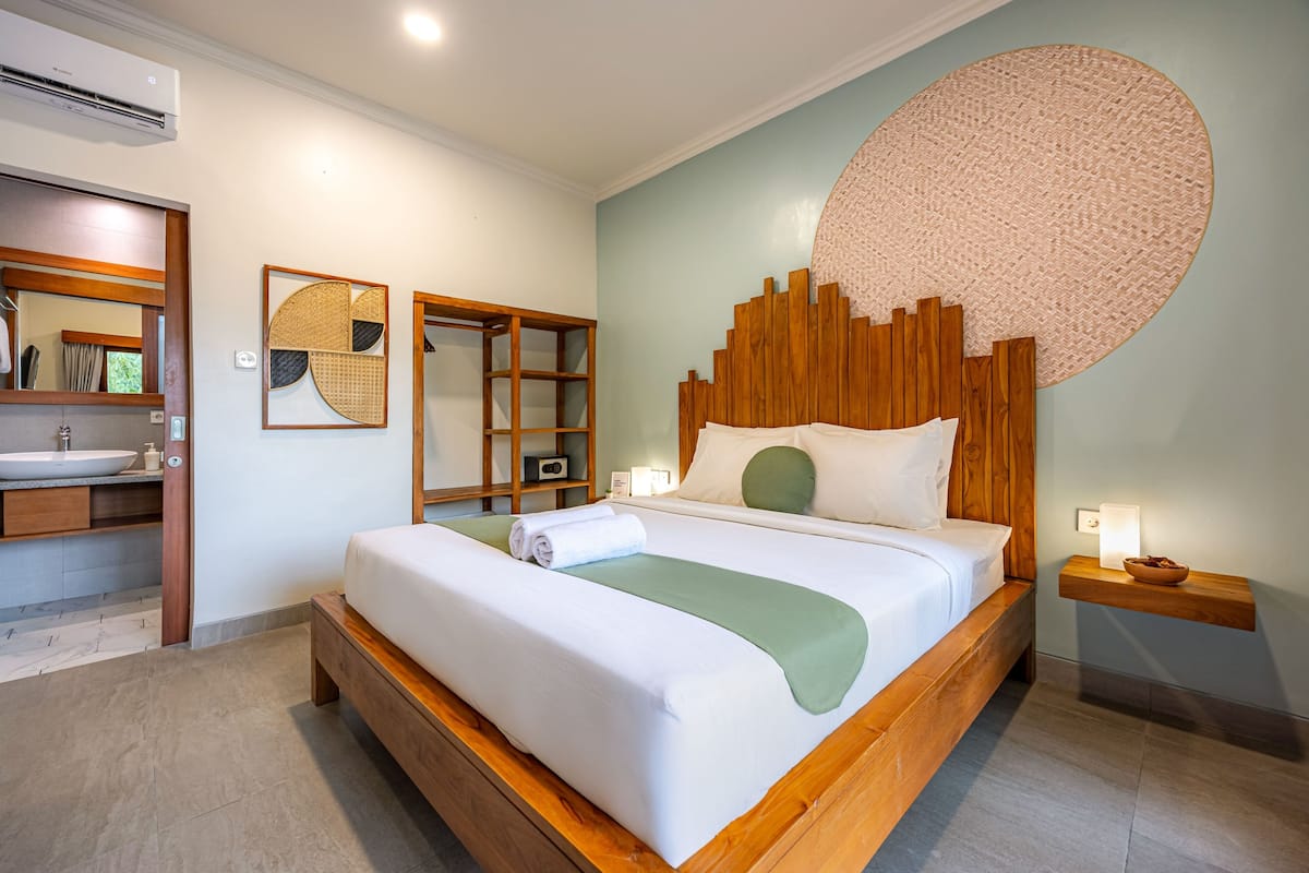 Une chambre à coucher moderne avec un lit en bois, un grand miroir, une table de chevet avec une lampe et un tapis rond fixé au mur.