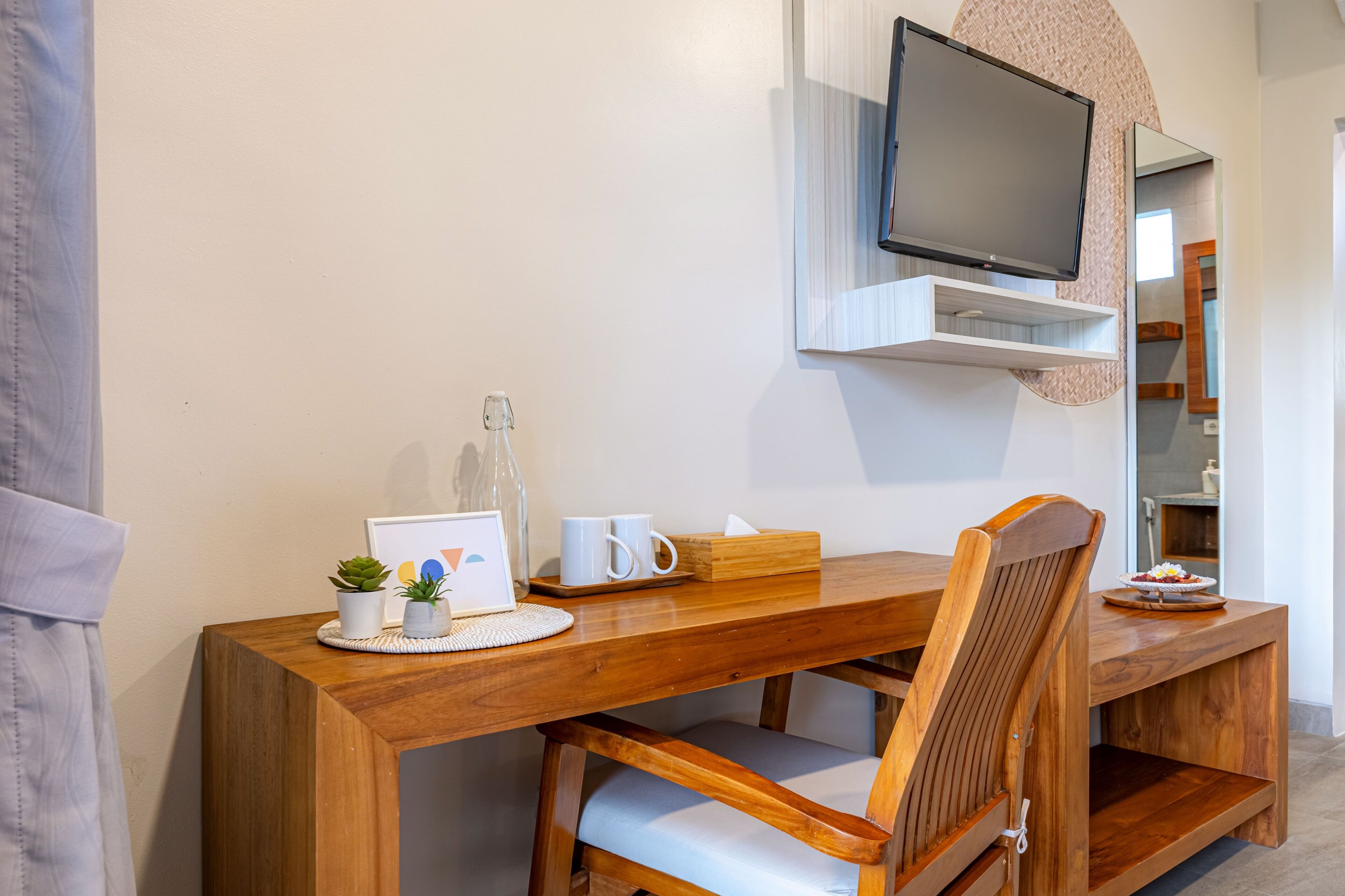 Una mesa de comedor de madera con sillas, un televisor montado encima y una planta pequeña sobre la mesa.