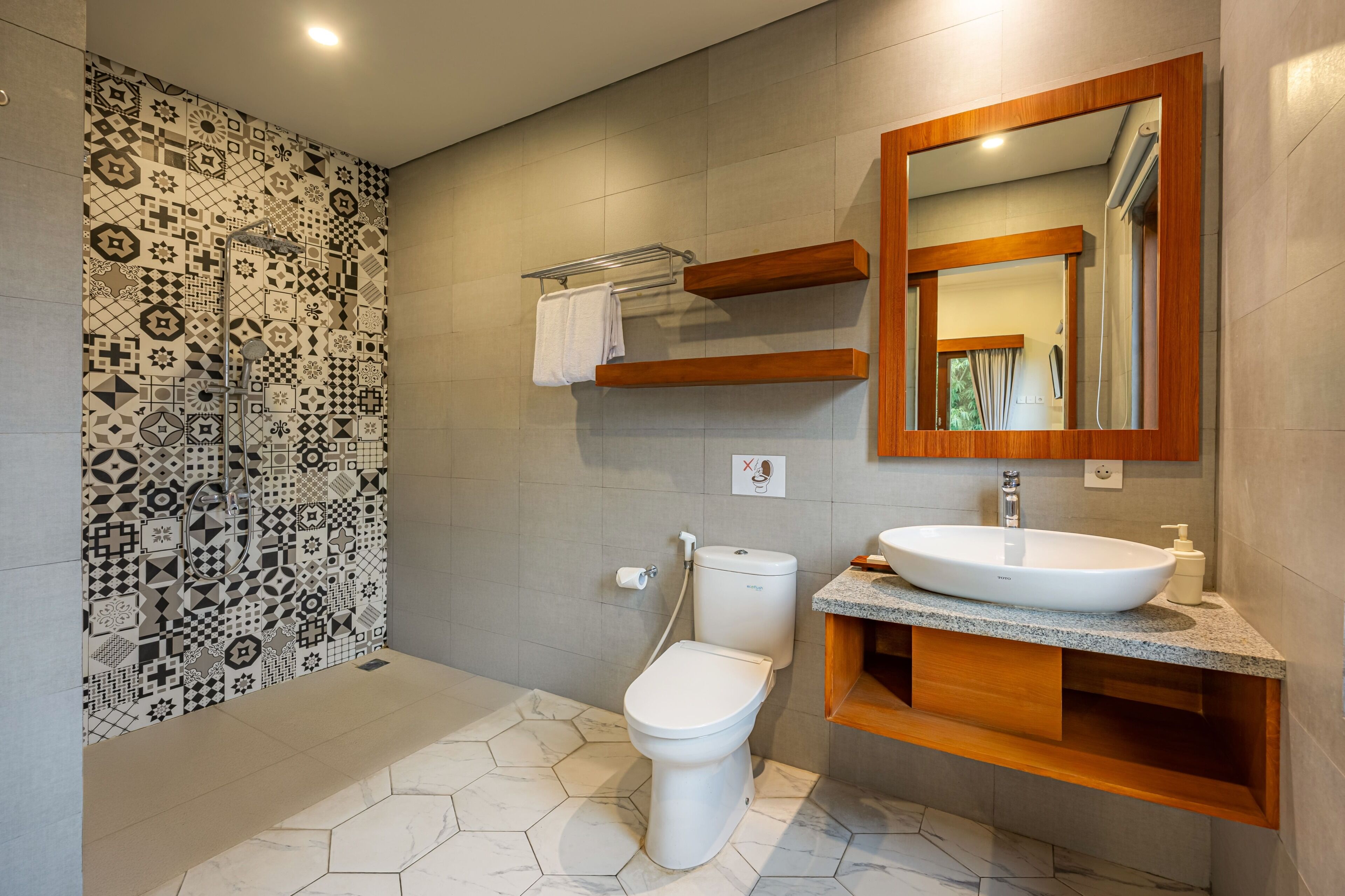 Un baño moderno con pared estampada, inodoro, lavamanos con espejo y zona de ducha.