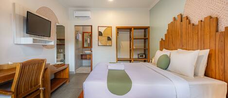A hotel room with a wooden bed, a desk, a chair, a television, and a wardrobe.