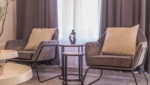 Ein modernes Wohnzimmer mit zwei grauen Sesseln, einem kleinen runden Tisch und einer dekorativen Skulptur.