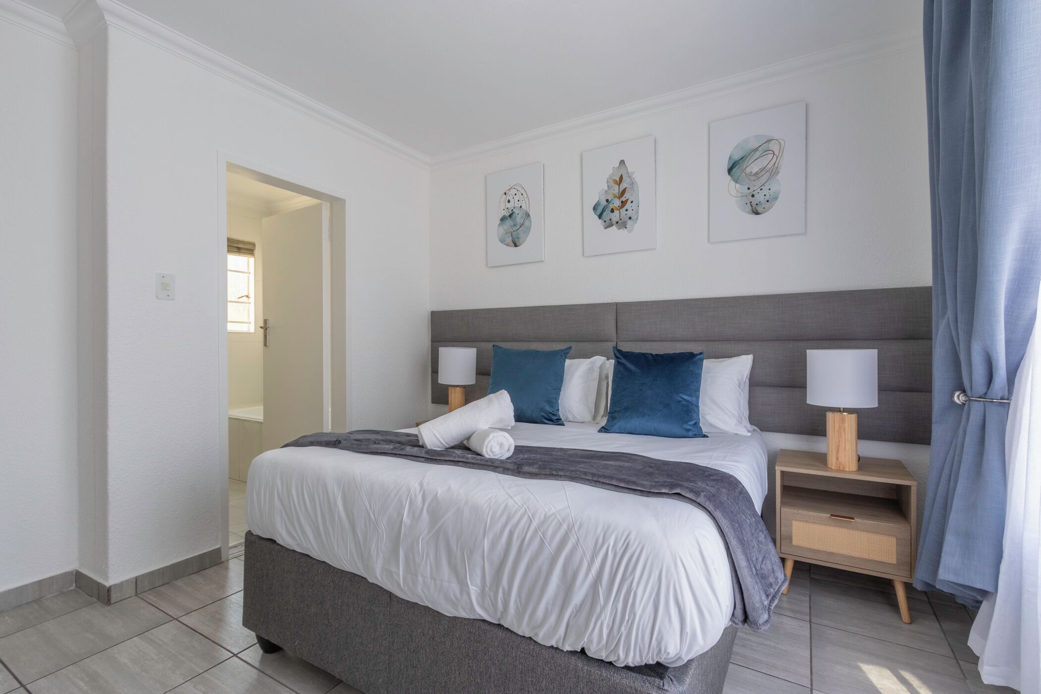 A modern bedroom with a large bed, two bedside tables, and artwork on the wall.