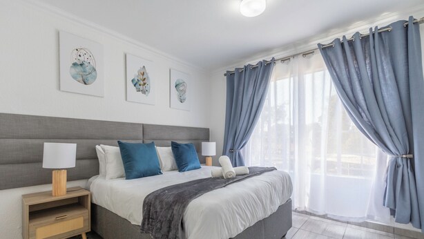 Ein modernes Schlafzimmer mit einem großen Bett, Nachttischen und einem Bild an der Wand.