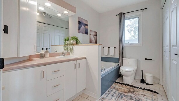 A modern bathroom with a sink, mirror, and toilet. - Stylish 2BR by Ottawa River (Gatineau)
