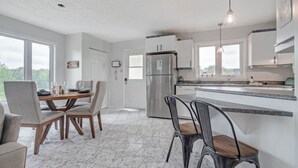 Et moderne køkken med spiseplads, store vinduer og udsigt til det fri.