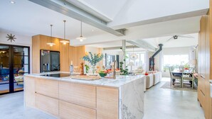 Una cucina moderna con un'isola grande, illuminazione a sospensione e vista sull'area pranzo.