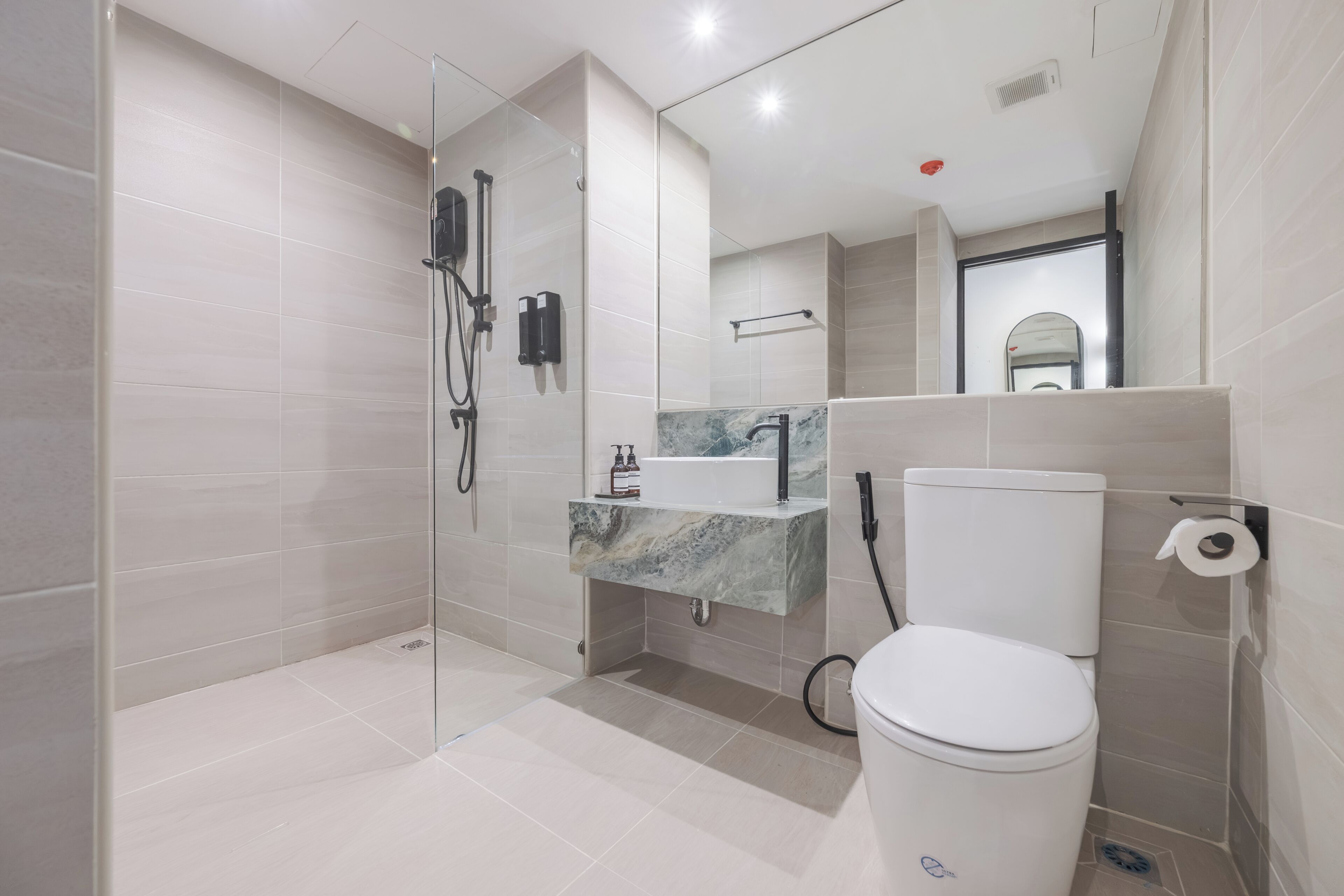 Ein modernes Badezimmer mit Duschkabine aus Glas, Marmorwaschbecken und Toilette.