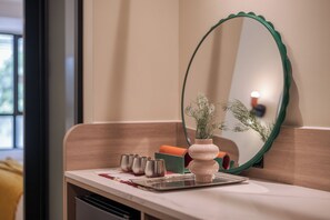 A bathroom with a mirror, a sink, a trash bin, and a small potted plant. - LILYBETH HOTEL PRATUNAM (Bangkok)