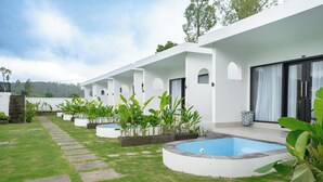 A modern building with a pool, surrounded by well-maintained grass and potted plants.