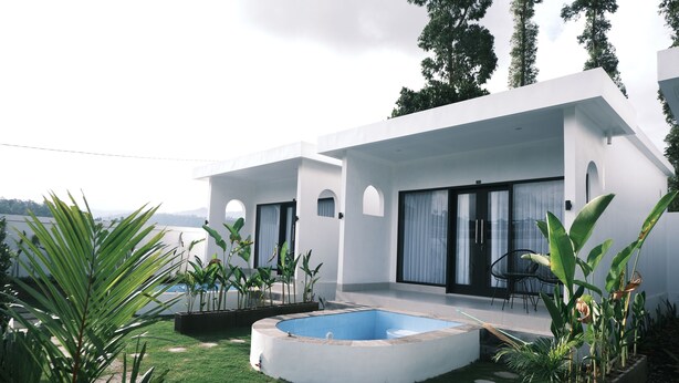 A modern house with a swimming pool, surrounded by lush greenery and a clear view of the mountains.