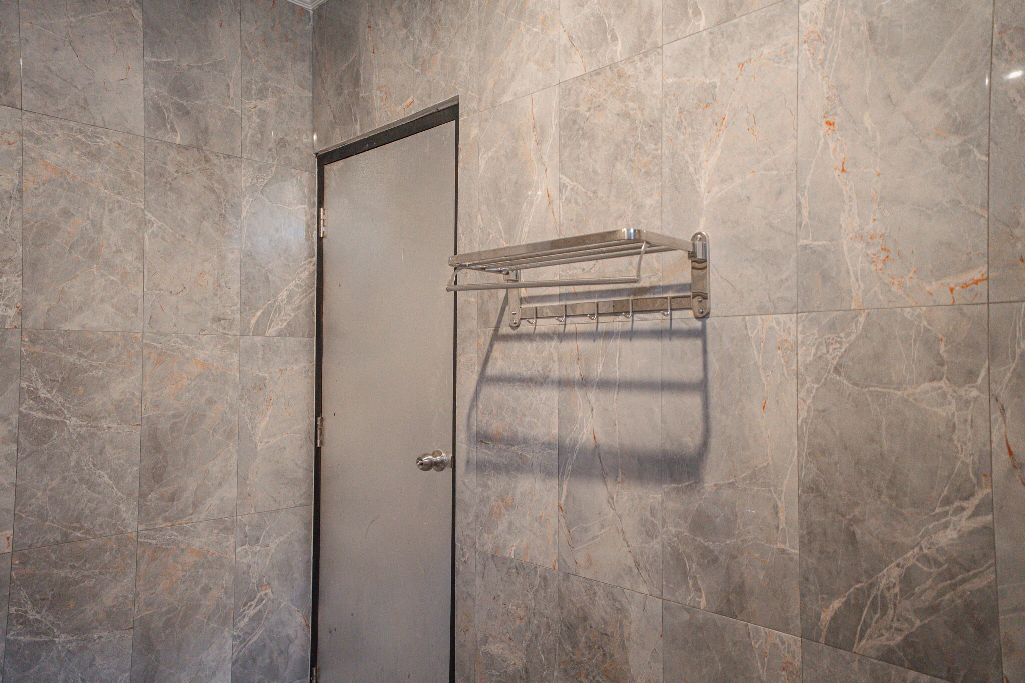 A bathroom with marble walls and a door.