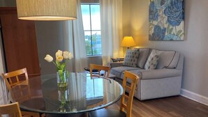 A dining area with a round glass table, wooden chairs, and a vase of flowers. - Beautiful Pool view -near Theme parks (Orlando)