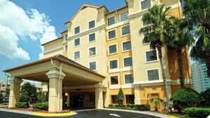 A multi-story hotel with a covered entrance and a palm tree in the foreground. - Beautiful Pool view -near Theme parks (Orlando)