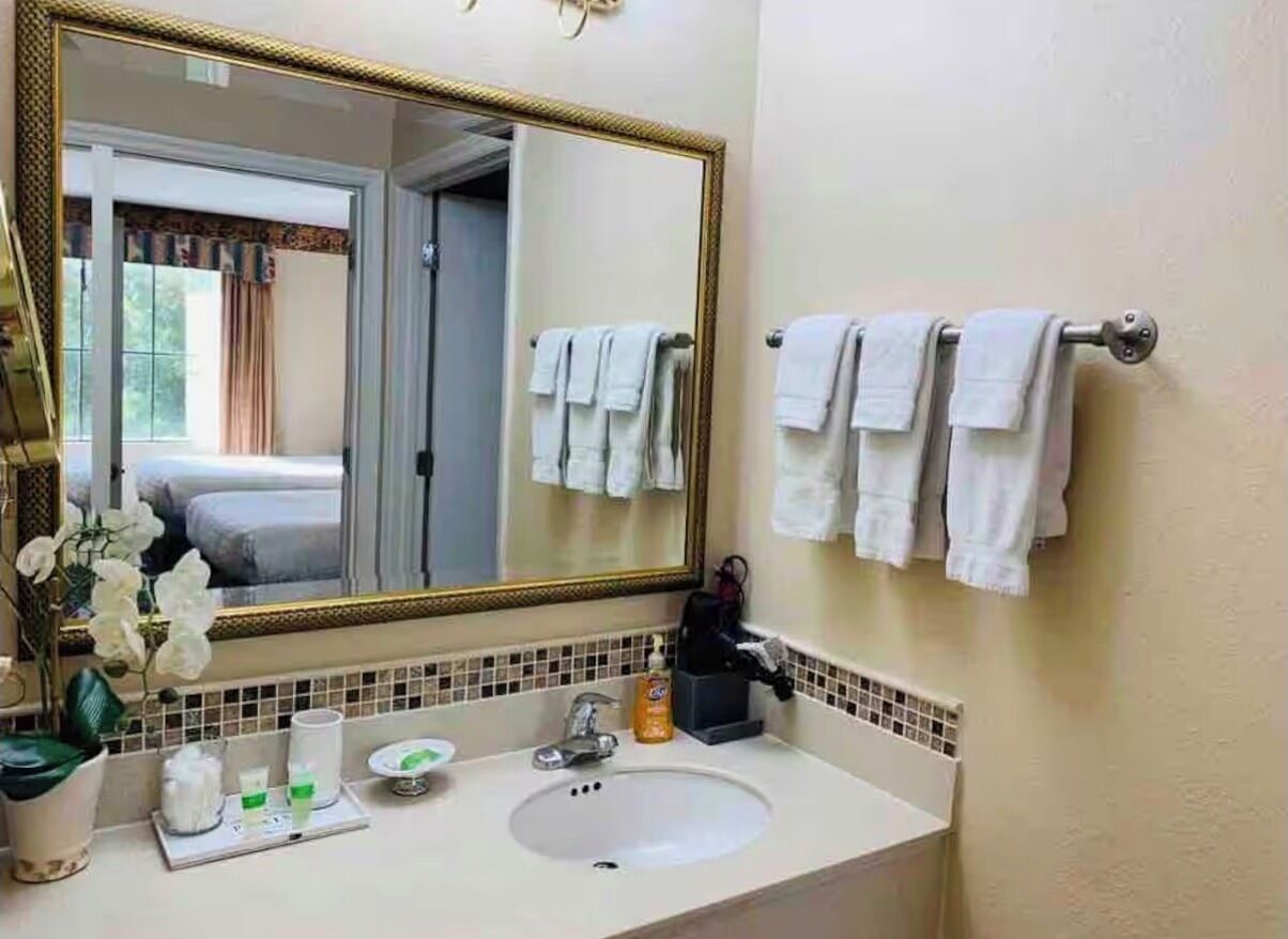 Un baño con un espejo grande, lavamanos blanco y barra para toallas.