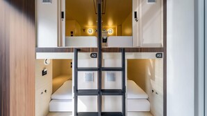 Habitación de hotel con literas, un escritorio pequeño y una escalera.