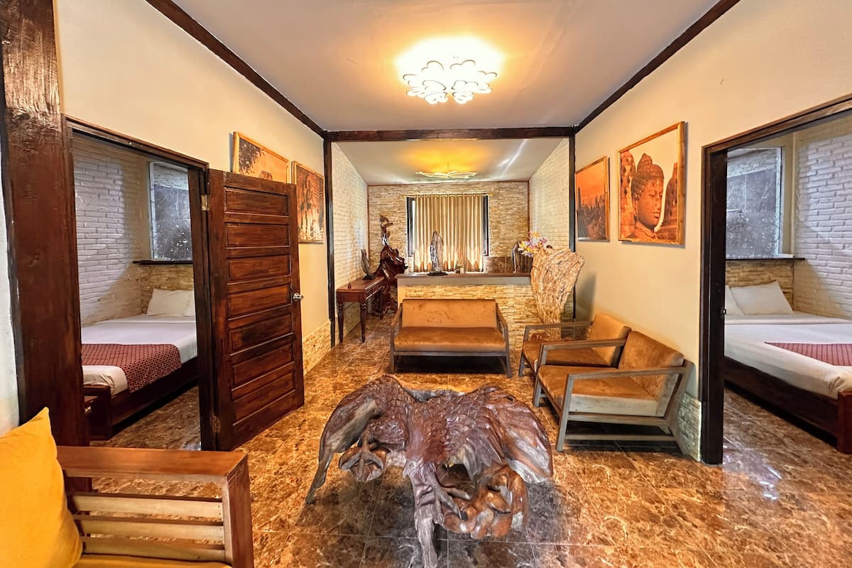 Une chambre d’hôtel comprenant un lit, une chaise en bois, un canapé, une sculpture décorative en bois et une cheminée.