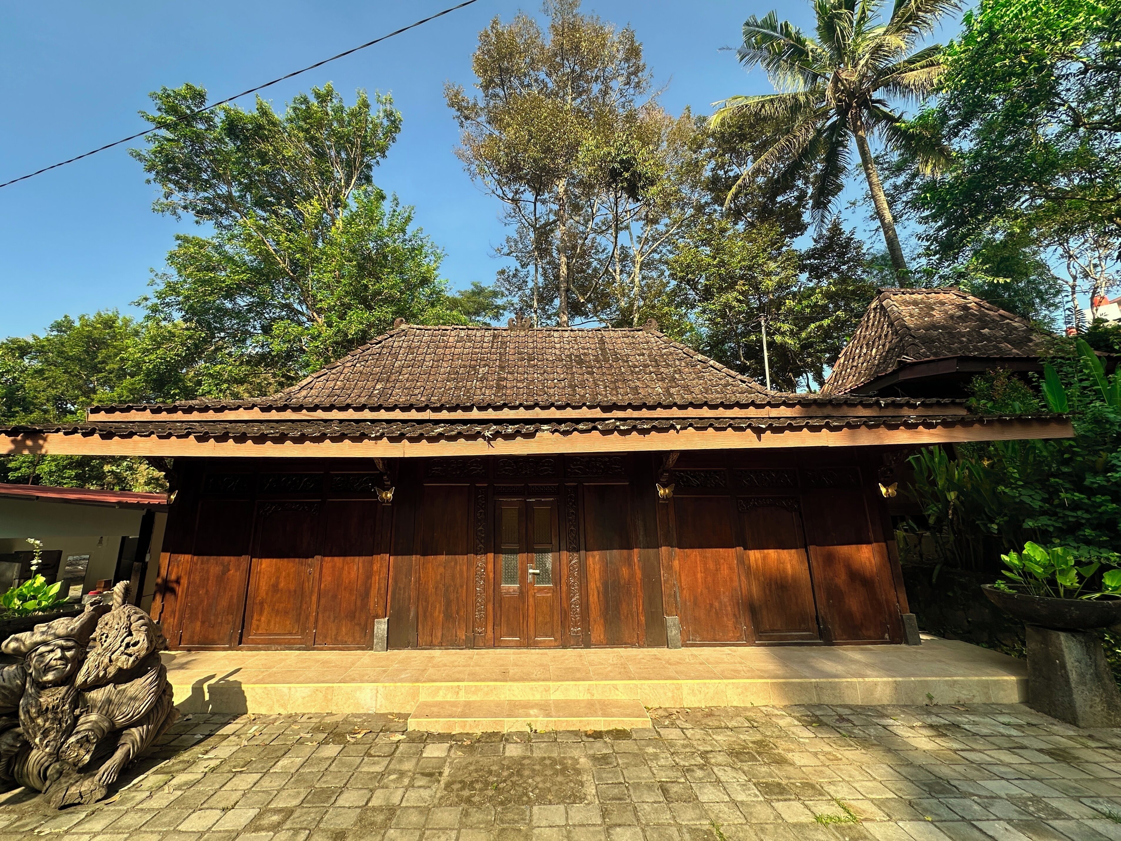A traditional wooden building with a tiled roof, large wooden doors, and a stone pathway leading to the entrance.