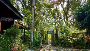 A garden pathway leading to a wooden structure with a tiled roof.
