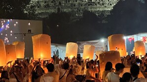 A crowd of people releasing sky lanterns in front of a temple.