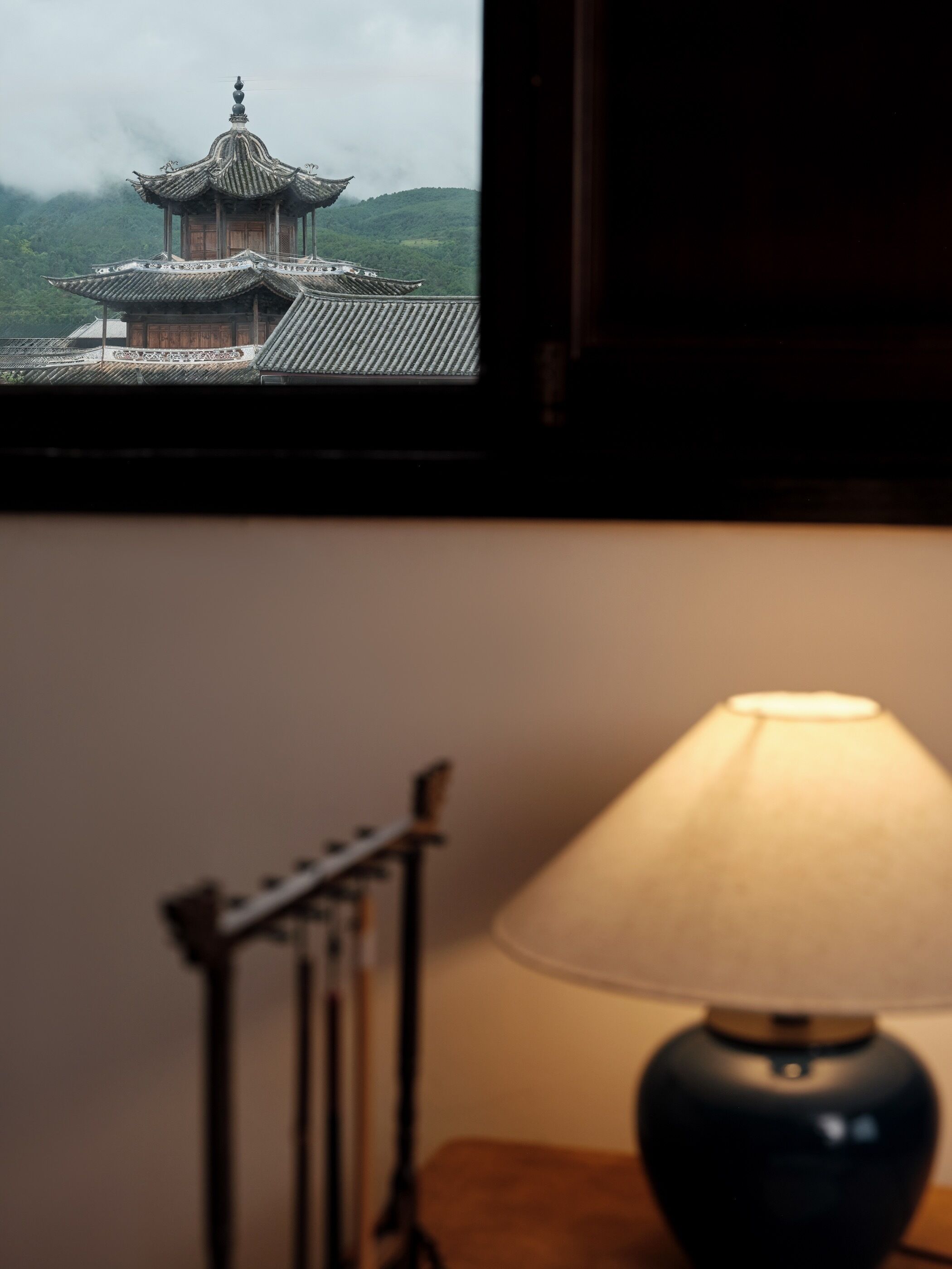 A traditional building with a tiled roof and a wooden structure, viewed through a window.