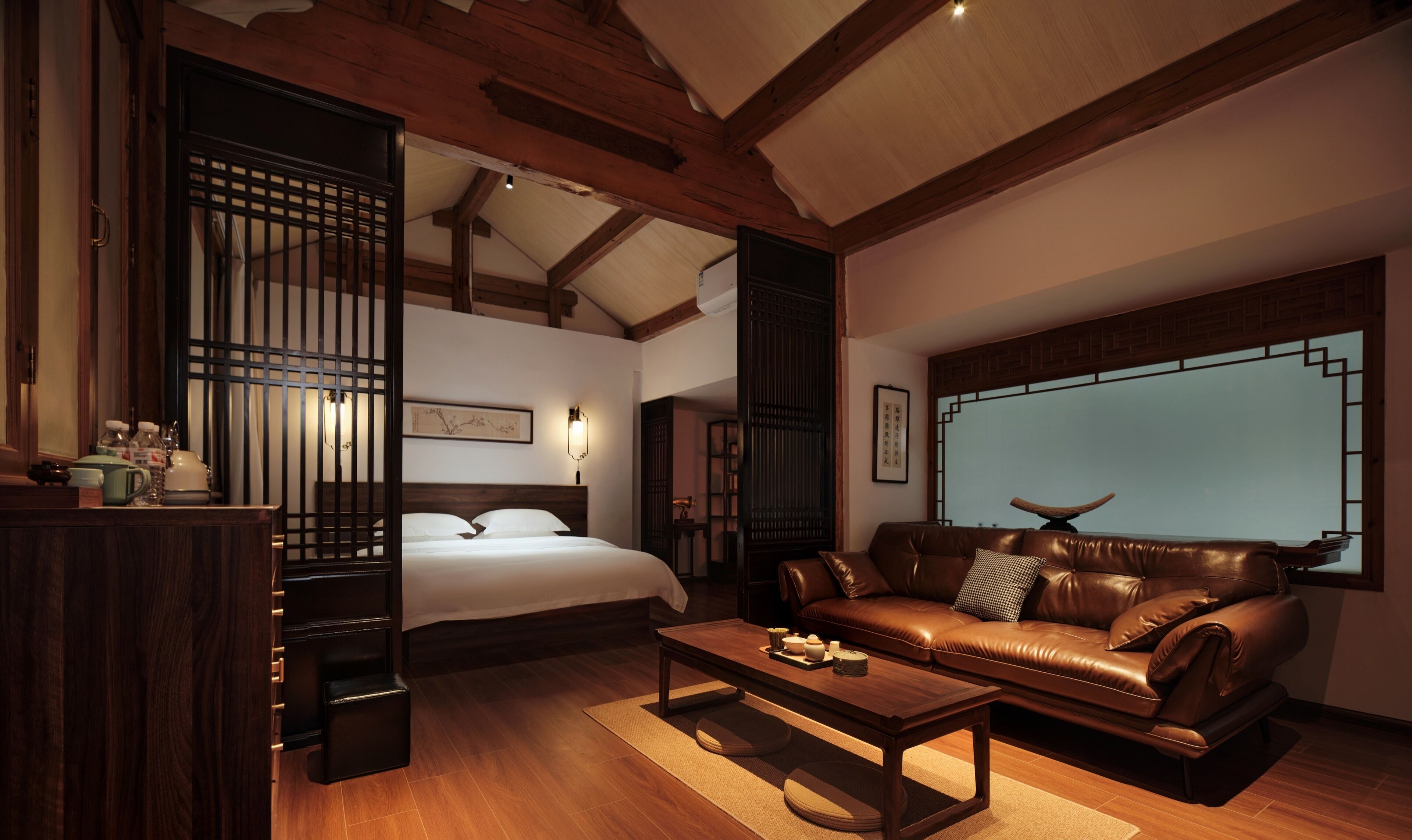 Una habitación de estilo japonés tradicional con una cama, un sofá de cuero y un ventanal grande.