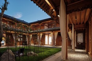 Un edificio de madera tradicional con un patio, que incluye una zona de estar y una mesa de madera.