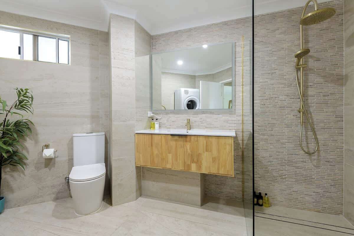 Une salle de bain moderne équipée de toilettes, d’un lavabo, d’un miroir et d’une douche.