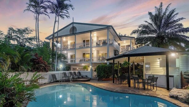 A multi-story building with a swimming pool, outdoor seating, and a covered patio area. - Top Floor Retreat – Walk to Beach & Town (Port Douglas)